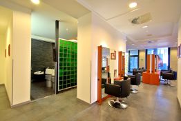Salonbereich mit Sitzecke und grüner Glasbausteinwand